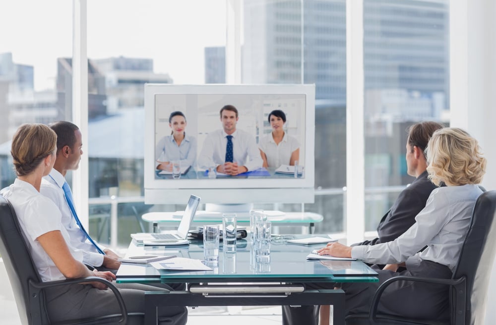 People in a conference room meeting with others joining virtually